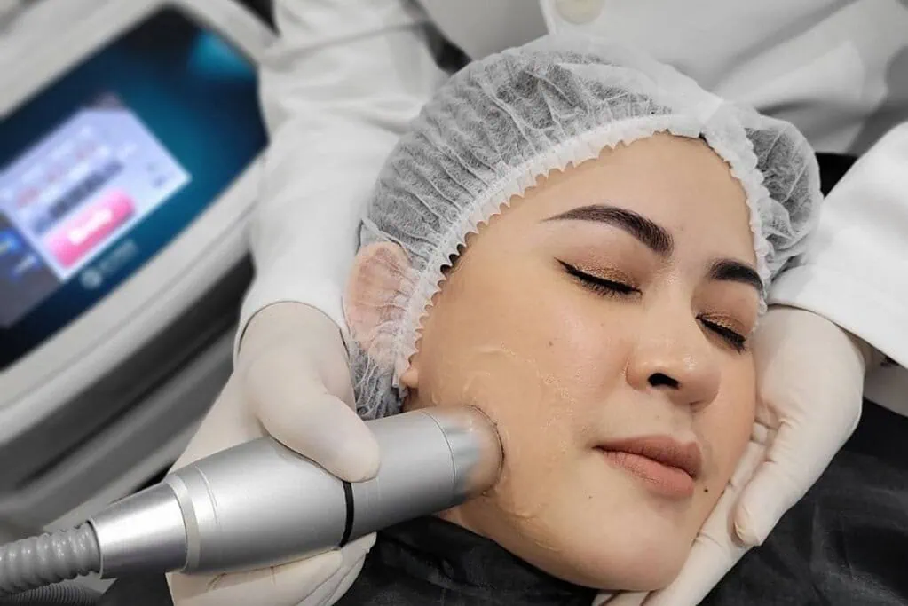 Woman receiving facial skin treatment with a handheld device and clear gel.