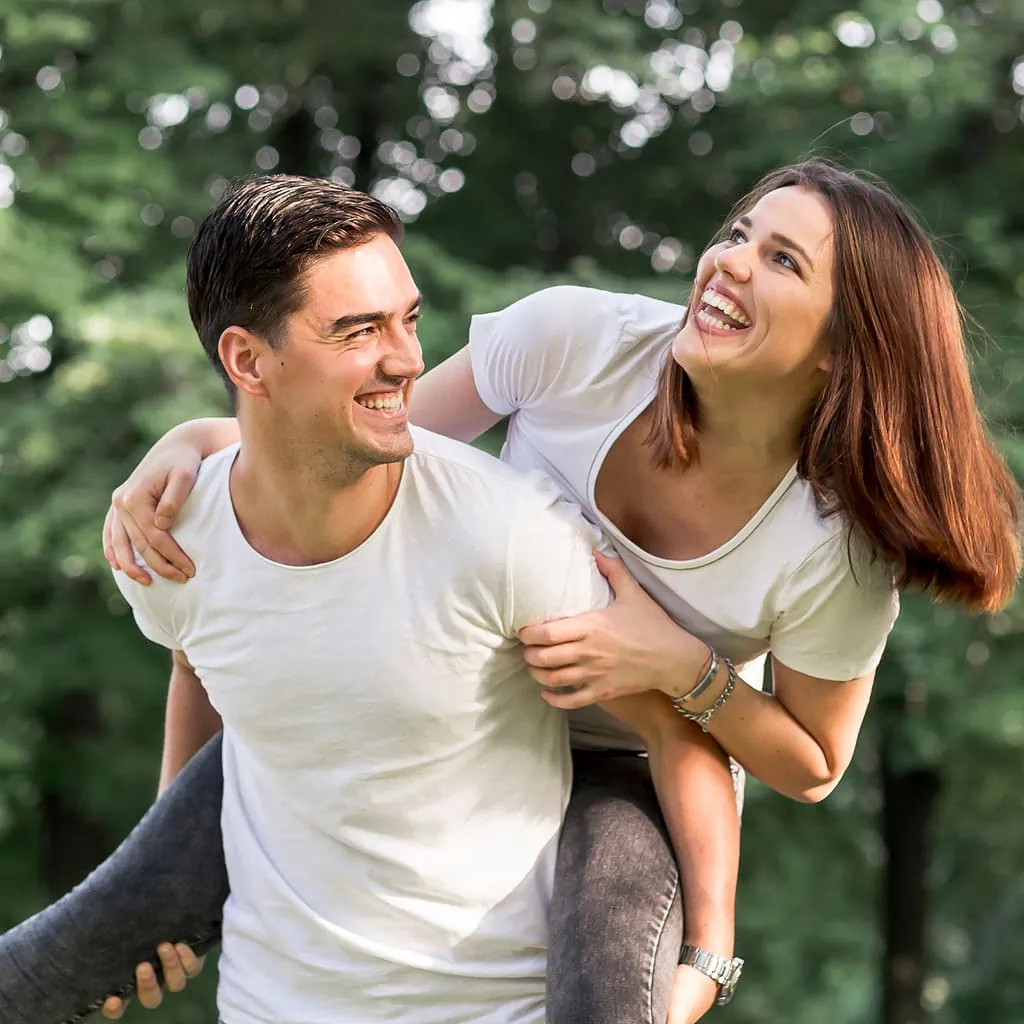Smiling couple enjoying a piggyback ride outdoors