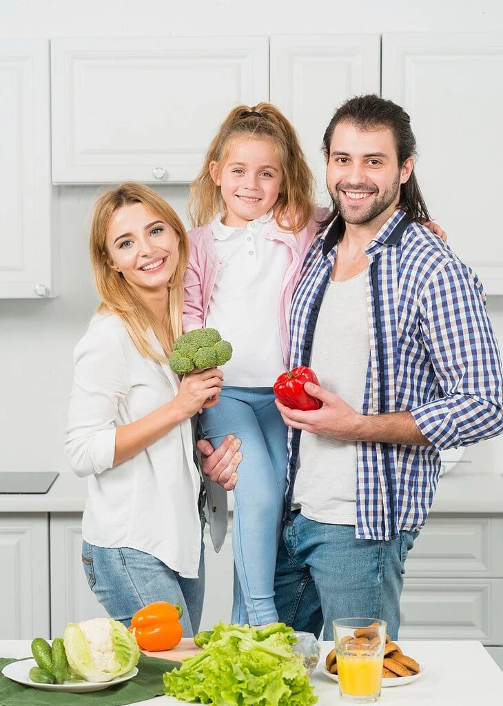 Happy family smiling in a kitchen with fresh vegetables