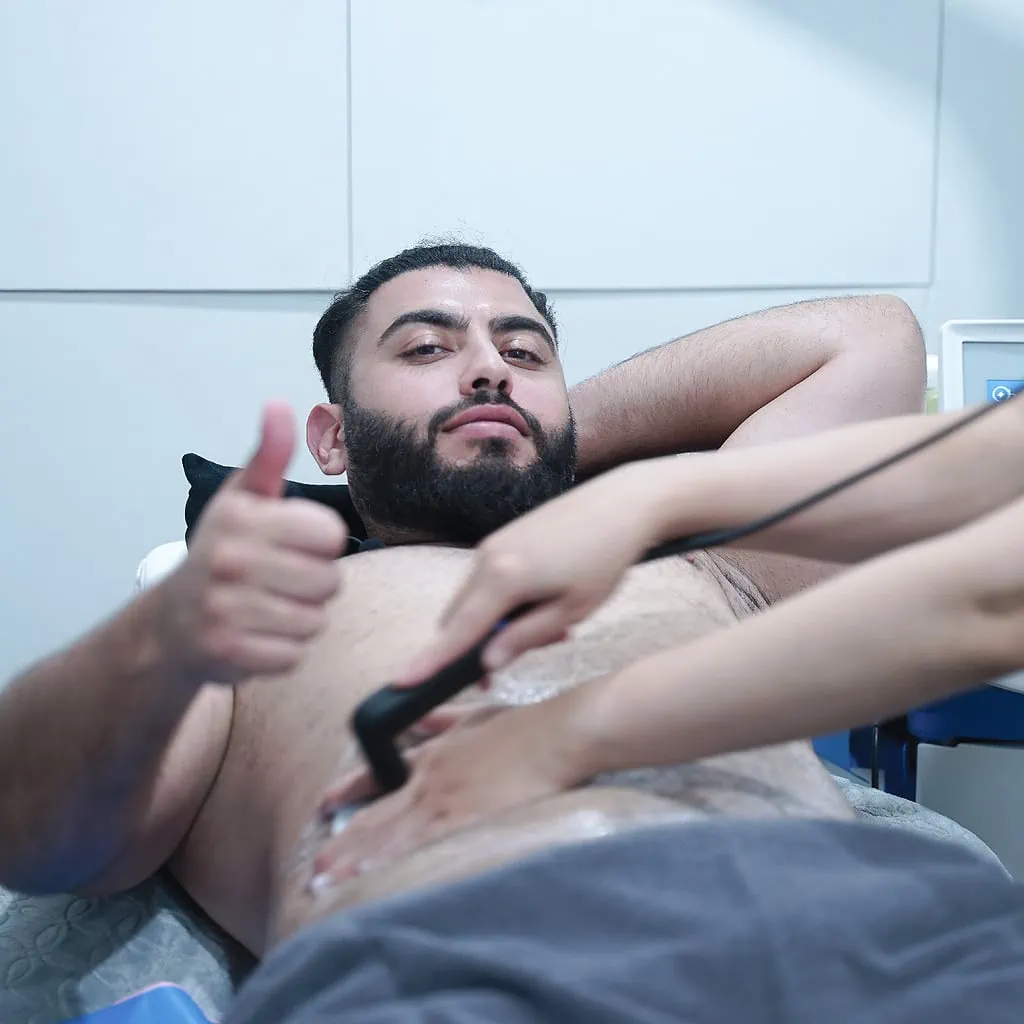 Man gives thumbs up during body contouring treatment with device and gel